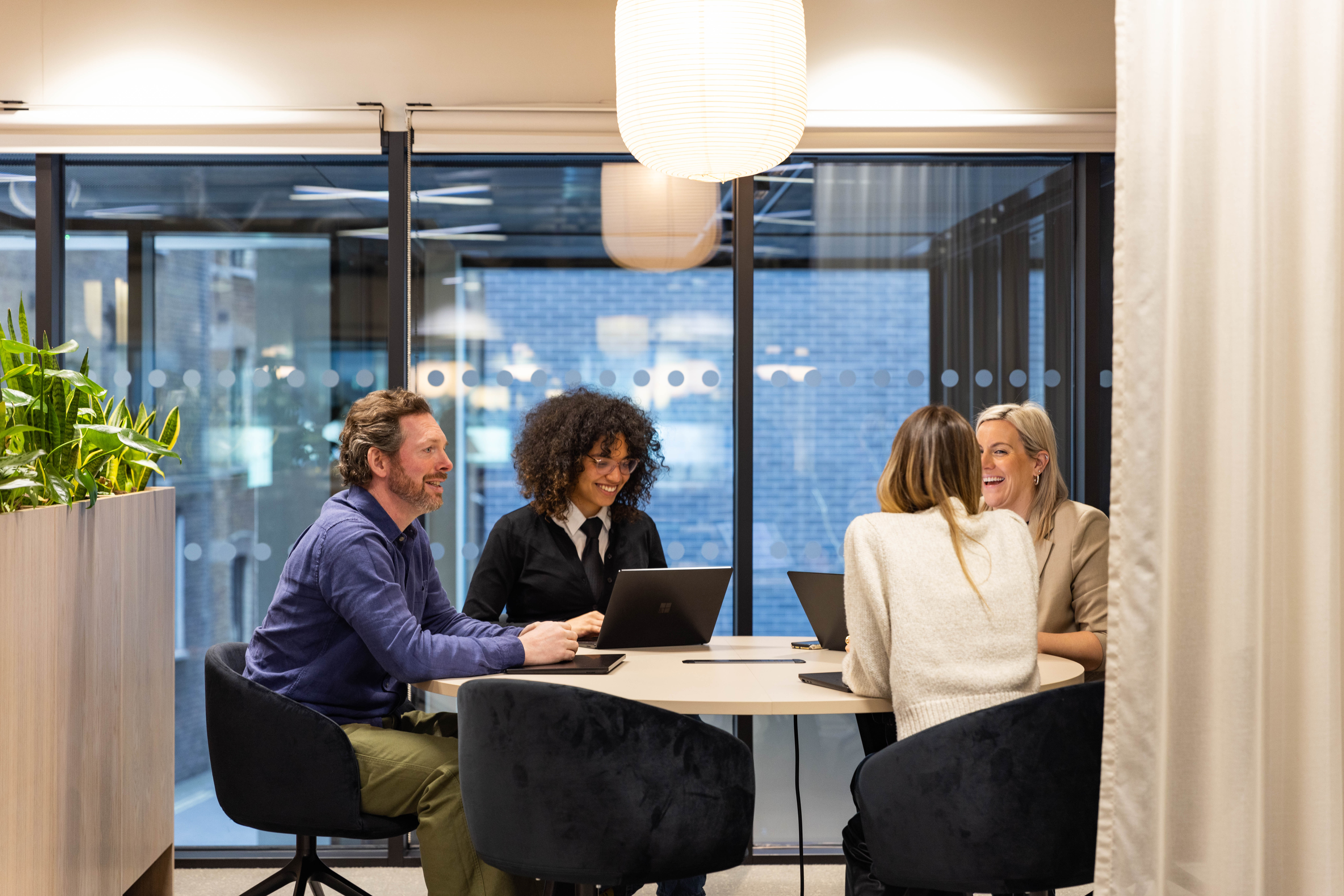 Four professionals collaborating around a table in a contemporary MYO meeting space.
