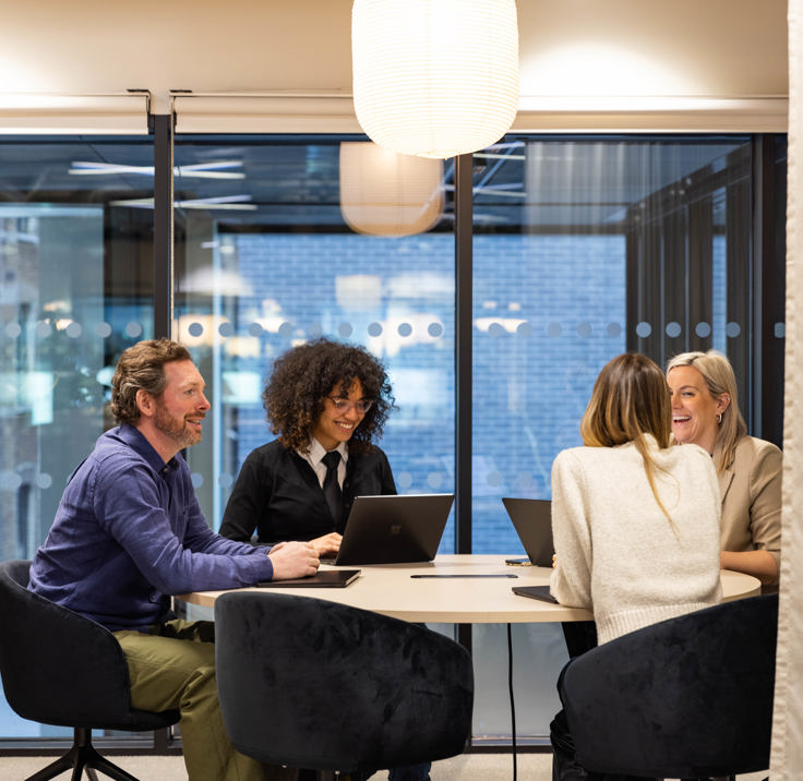 Four professionals collaborating around a table in a contemporary MYO meeting space.