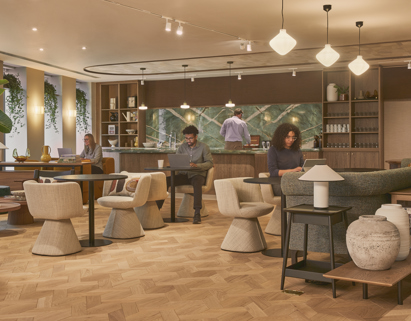 A modern breakout lounge with comfortable seating, café-style tables, a communal kitchen and people working in a contemporary office environment.
