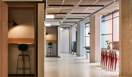 A contemporary workspace featuring private focus booths, communal seating, high tables and large windows in a modern office environment.