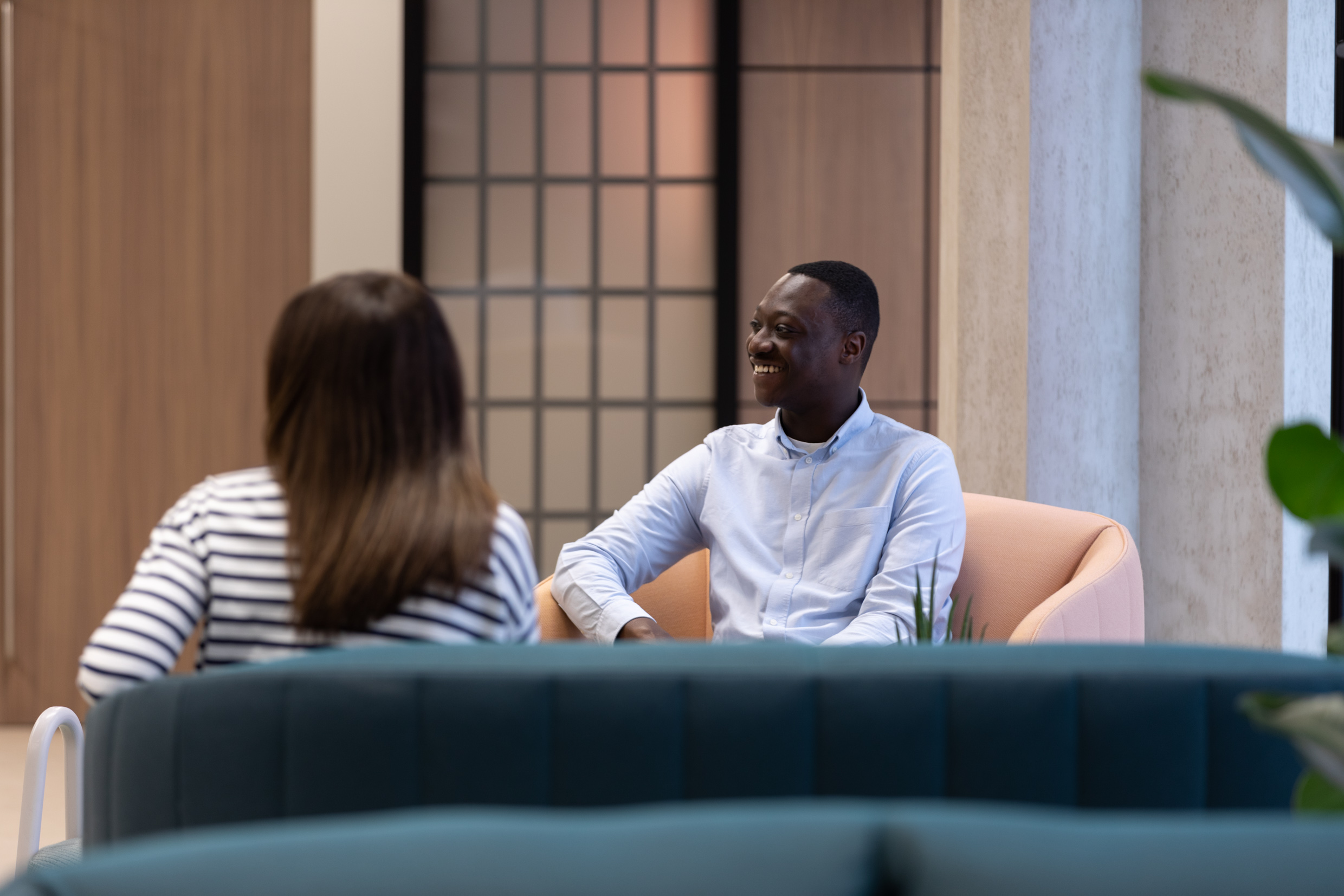 Two people having an informal meeting in a contemporary lounge area with comfortable seating and modern office interiors.