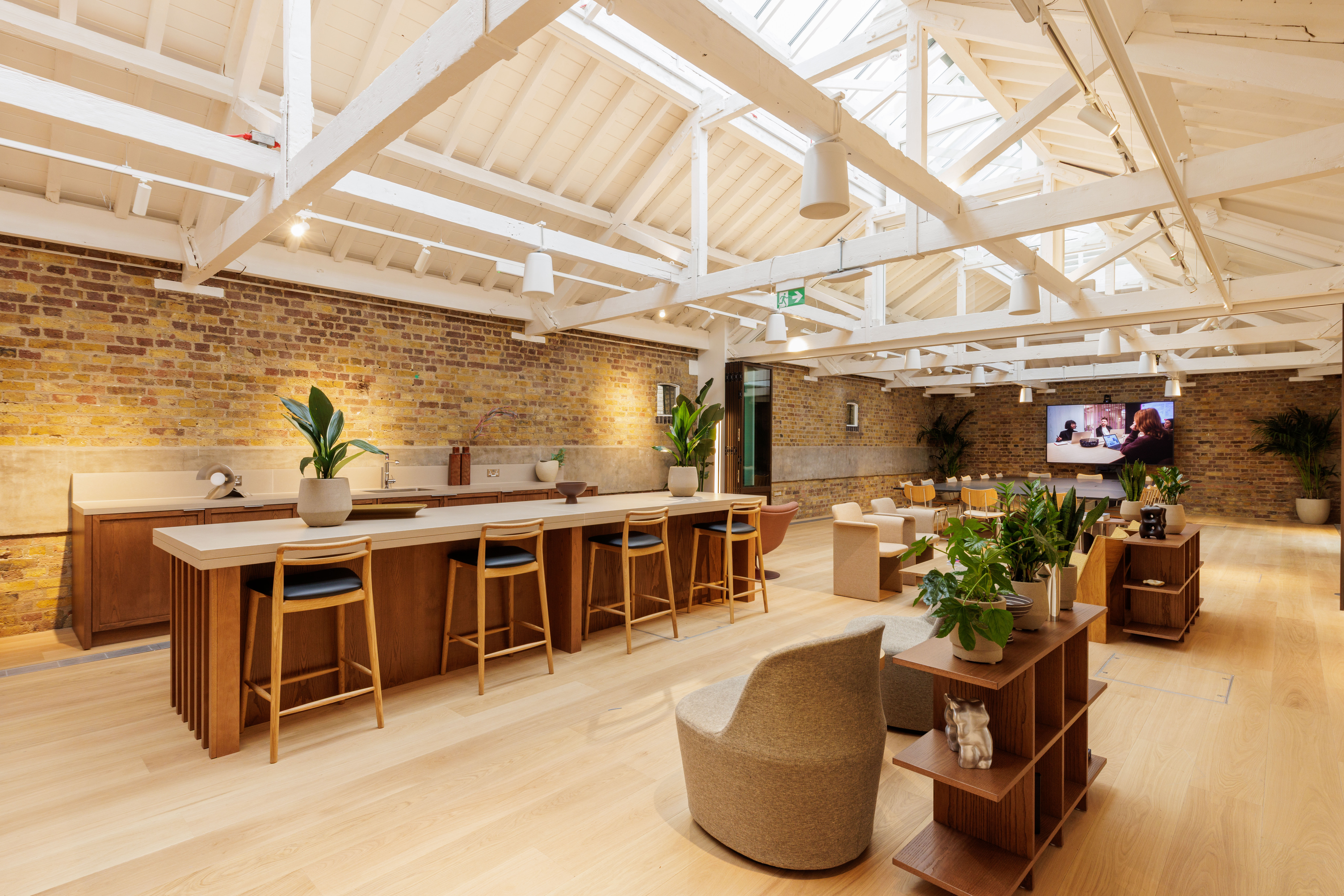Flexible event space with exposed brick walls, communal seating and a large kitchen island for meetings and gatherings.