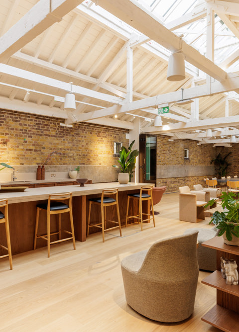 Flexible event space with exposed brick walls, communal seating and a large kitchen island for meetings and gatherings.