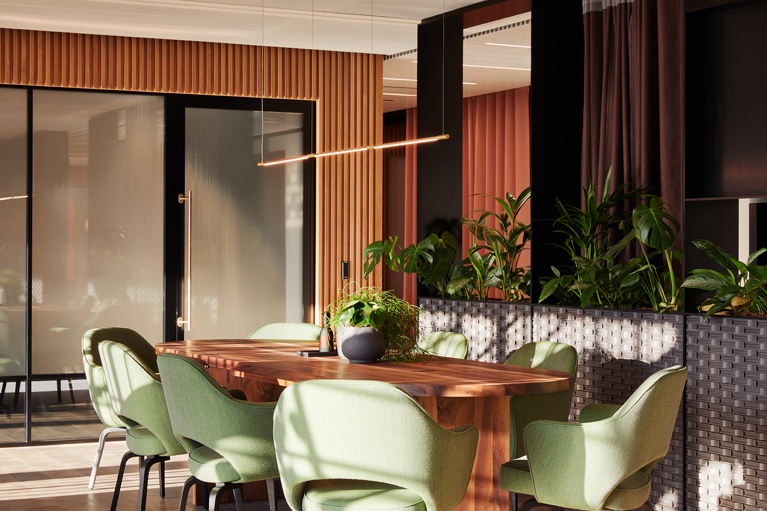 Collaborative meeting area at MYO Liverpool Street featuring a shared wooden table, comfortable seating and biophilic design elements within a contemporary workspace.