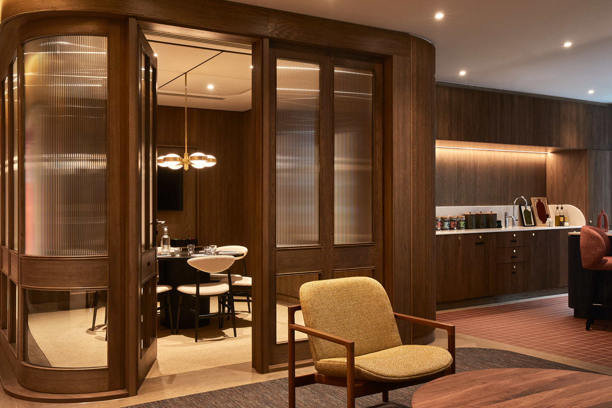 A contemporary workspace featuring a private meeting room with glazed timber doors, lounge seating and a communal kitchen with timber finishes.