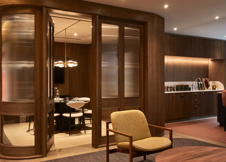 A contemporary workspace featuring a private meeting room with glazed timber doors, lounge seating and a communal kitchen with timber finishes.